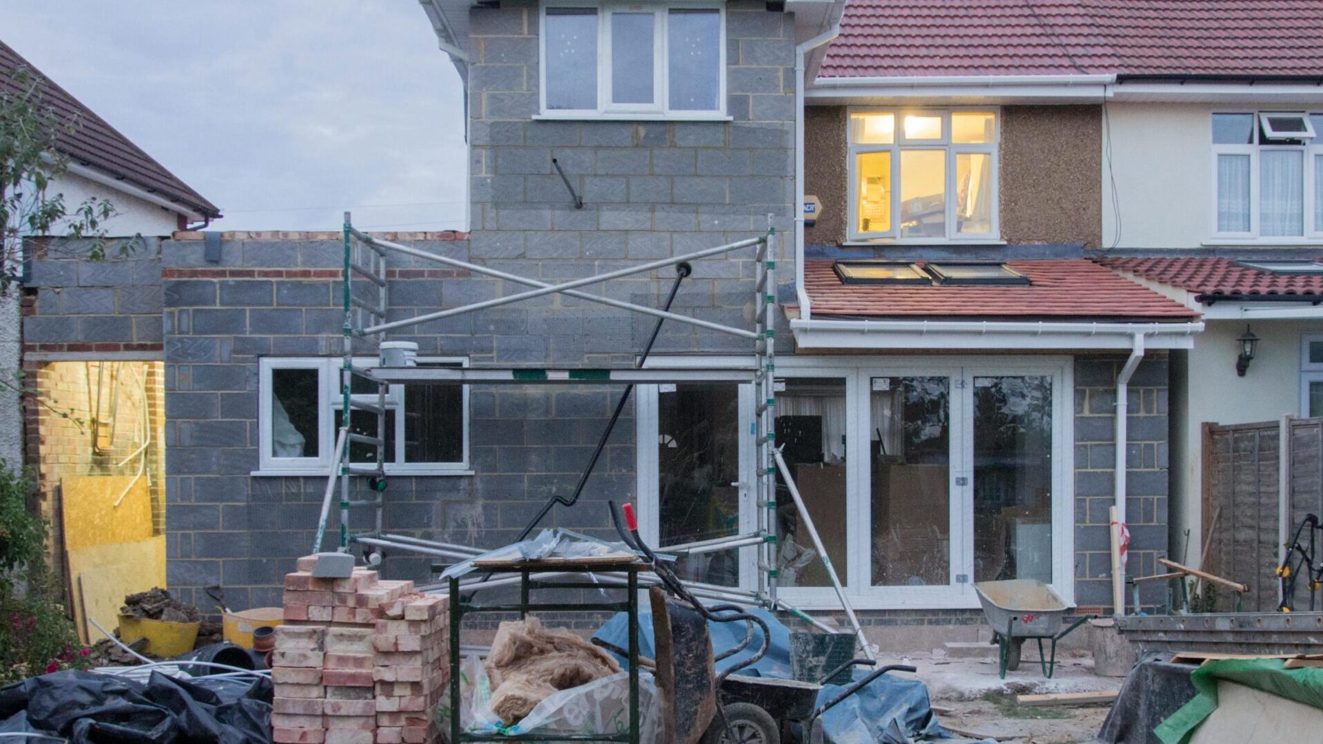 A suburban house undergoing major renovations with scaffolding and building materials.