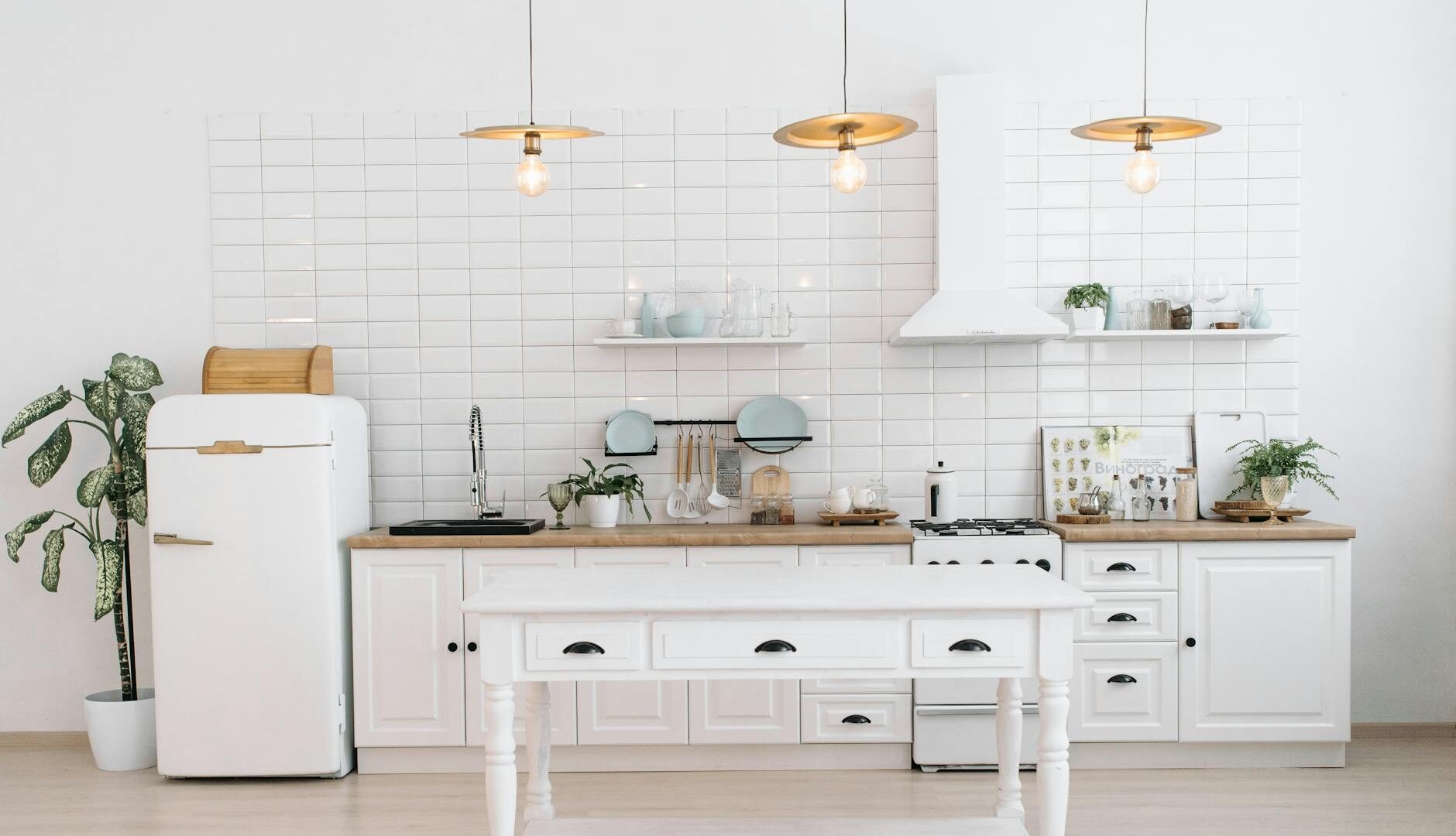 A bright, minimalist kitchen with vintage appliances, plants, and pendant lights.
